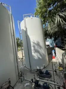 A large white tank sitting next to a tree.