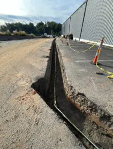 A hole in the ground that is being dug out of concrete.