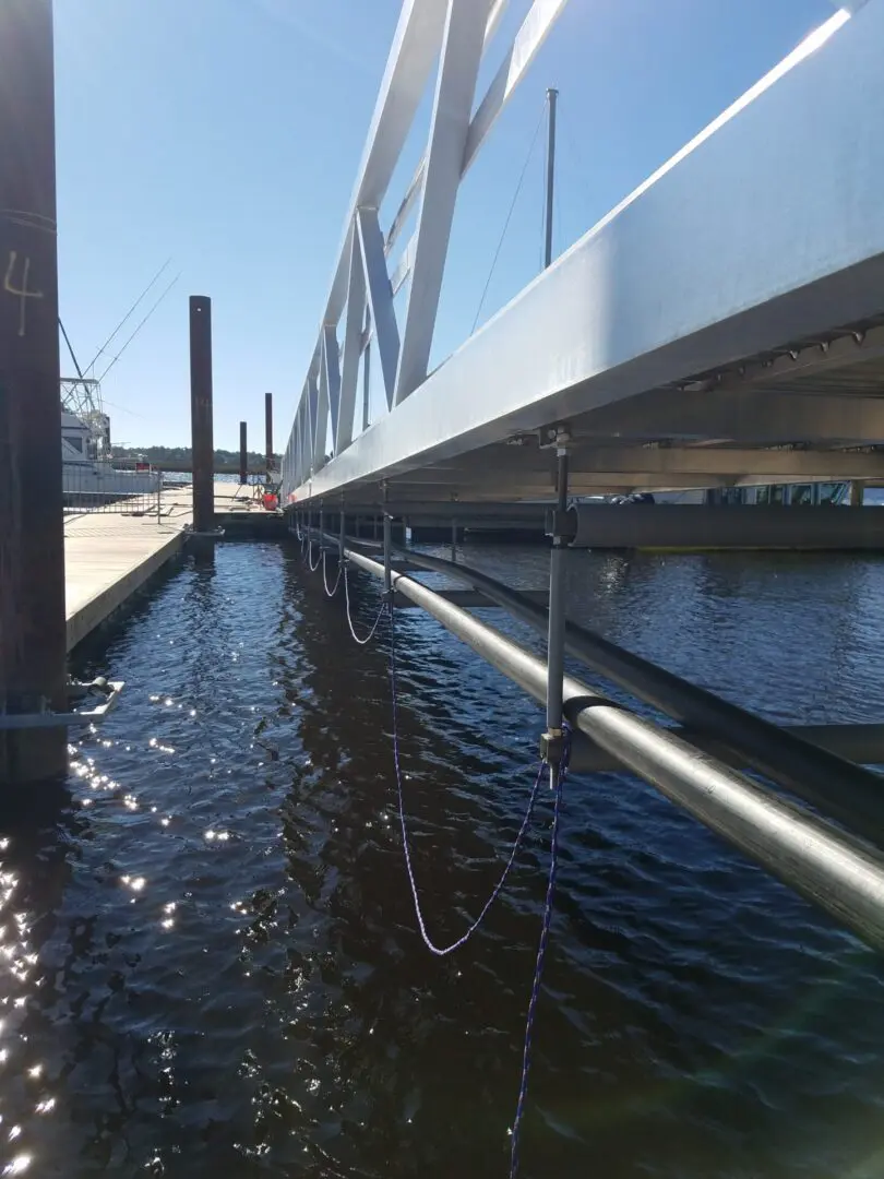 A bridge with water running over it and some wires hanging from the side of it.