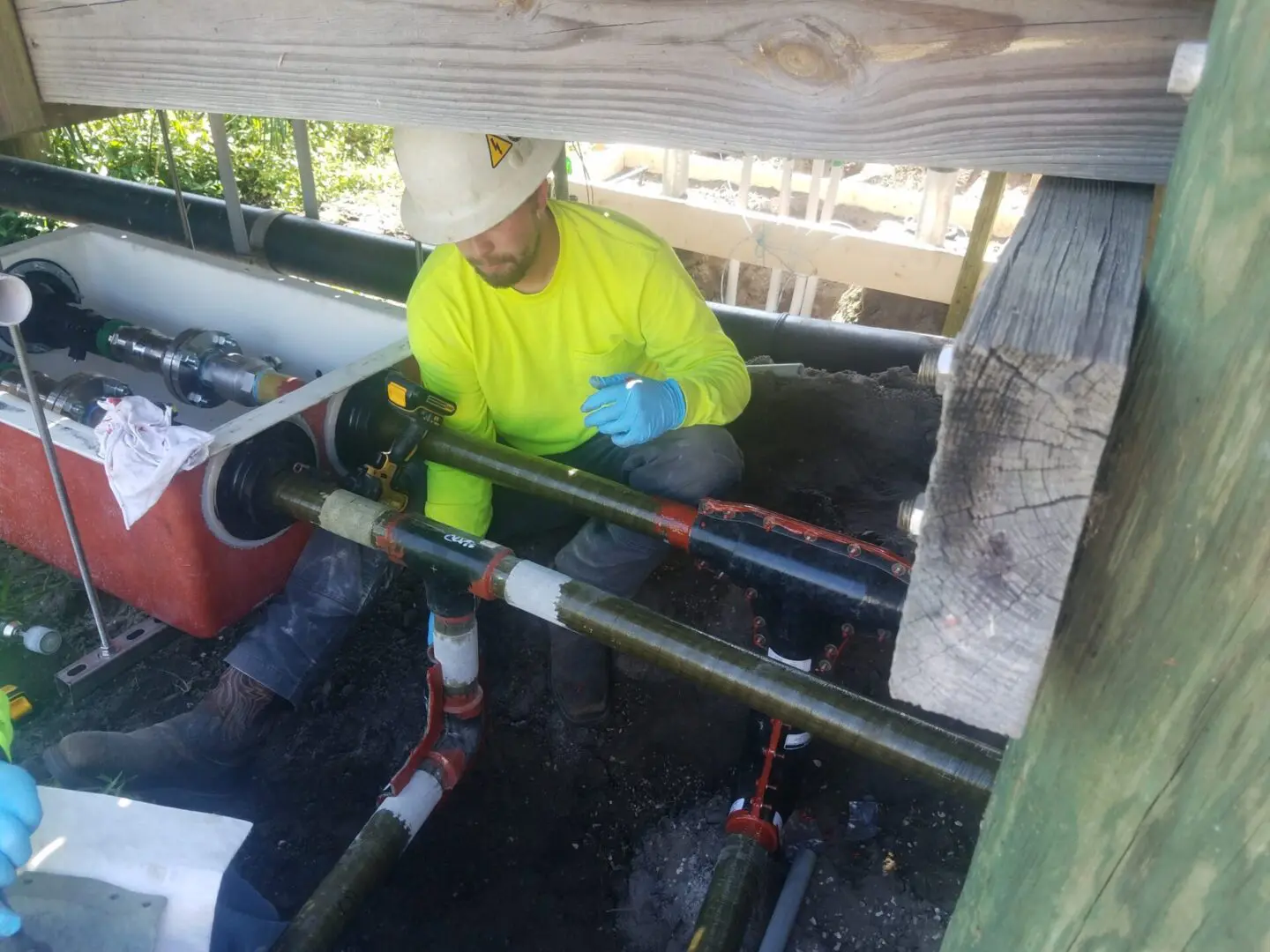 A man in yellow shirt working on pipes.