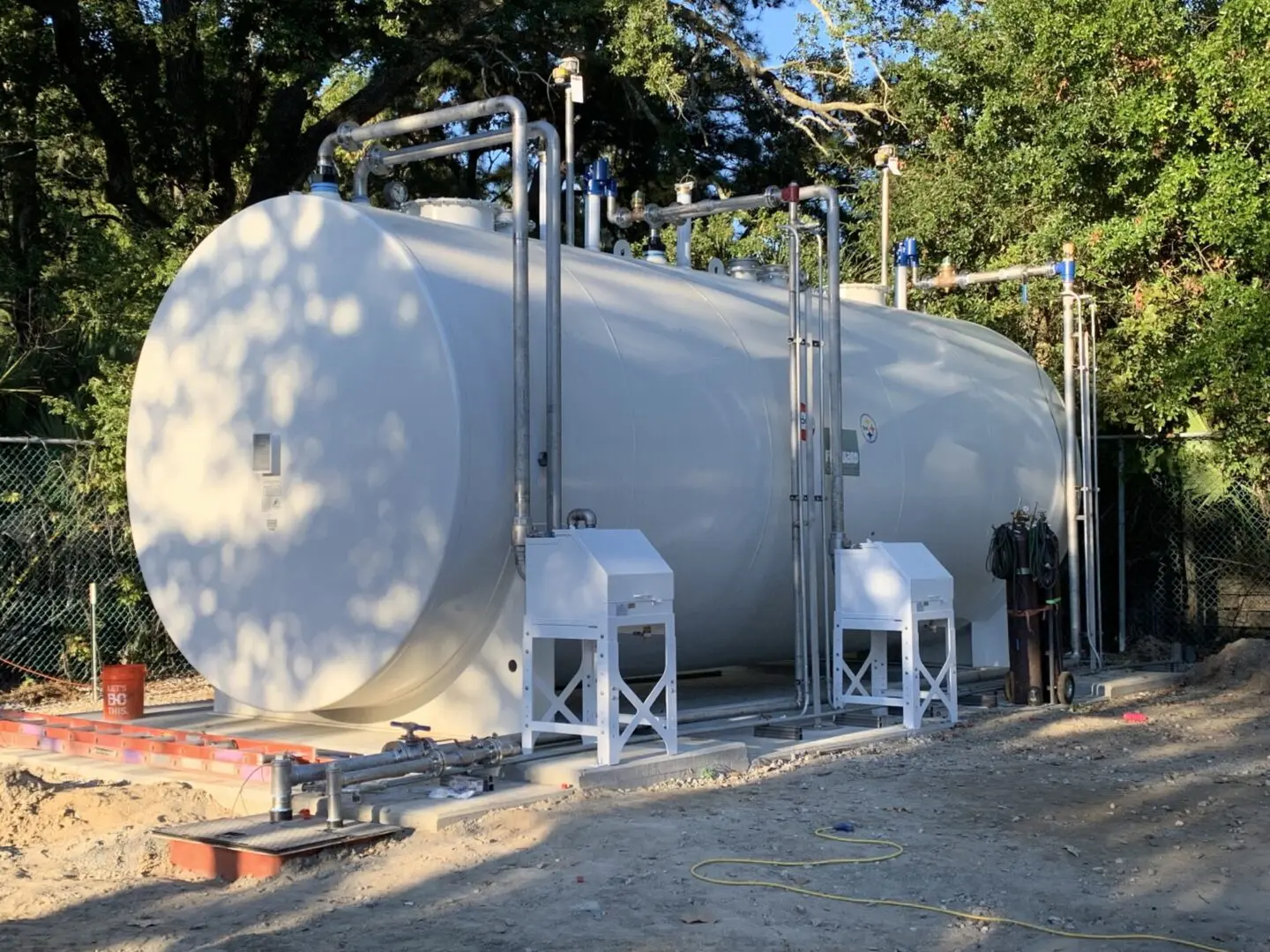 A man standing next to a large white tank.