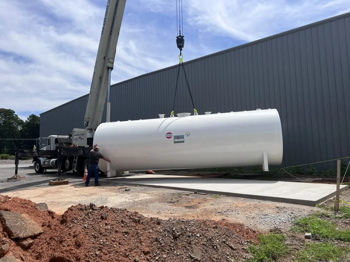 A large white tank being lifted by crane.