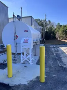 A white tank sitting next to two yellow poles.